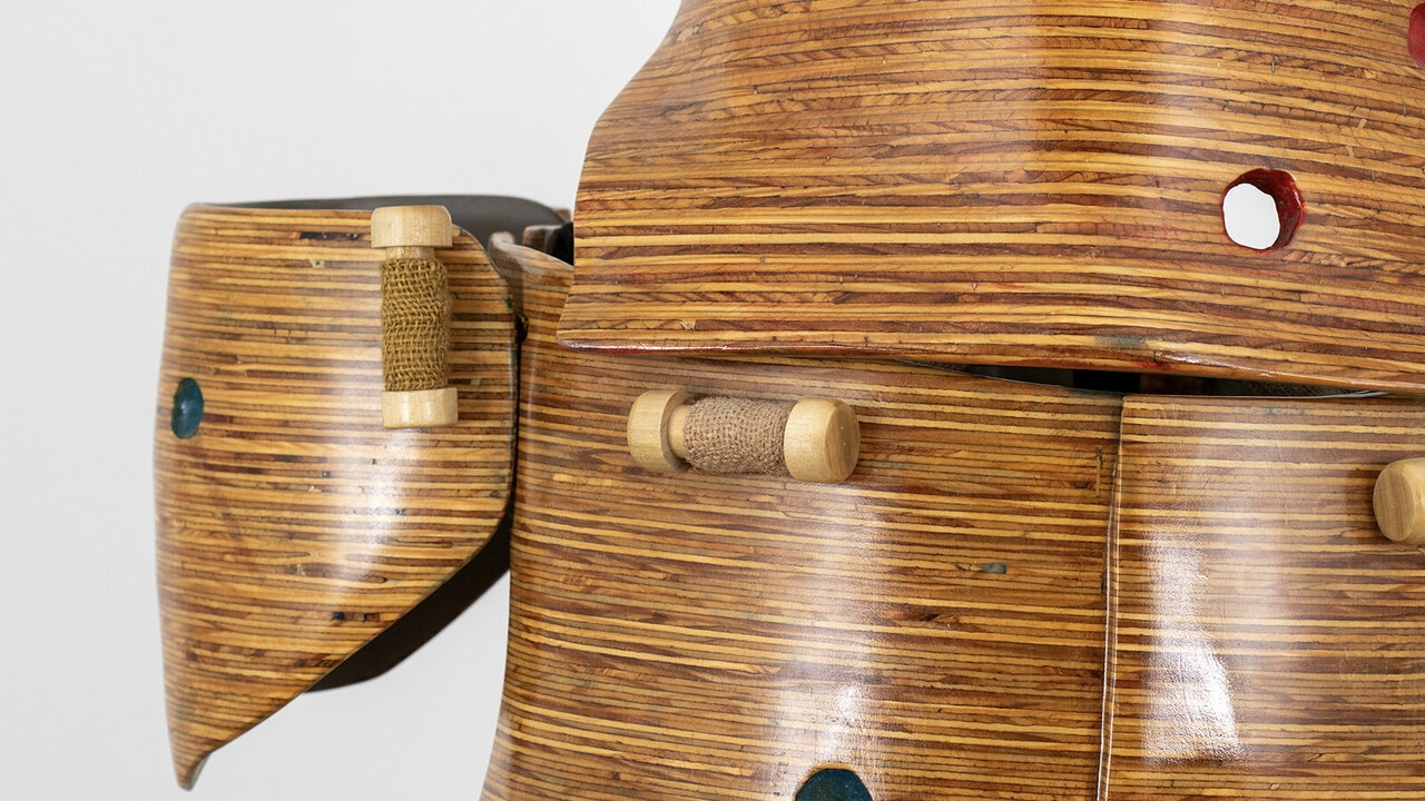 Image shows a wooden suit of armor that is held together by wooden spindles and burlap straps mimicking buttons
