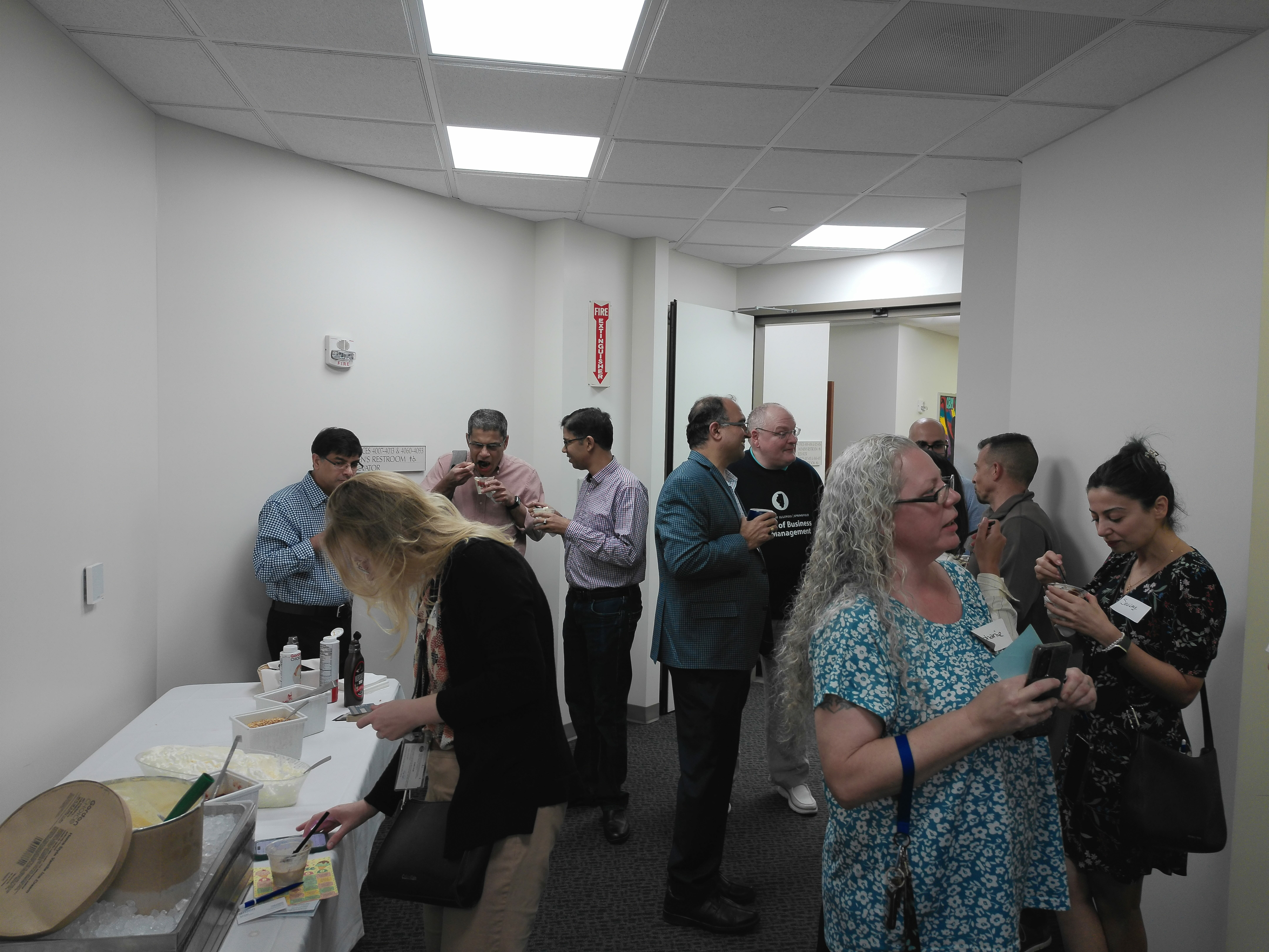 Four Scoop & Socialize attendees stand together in the College of Business and Management hallway.