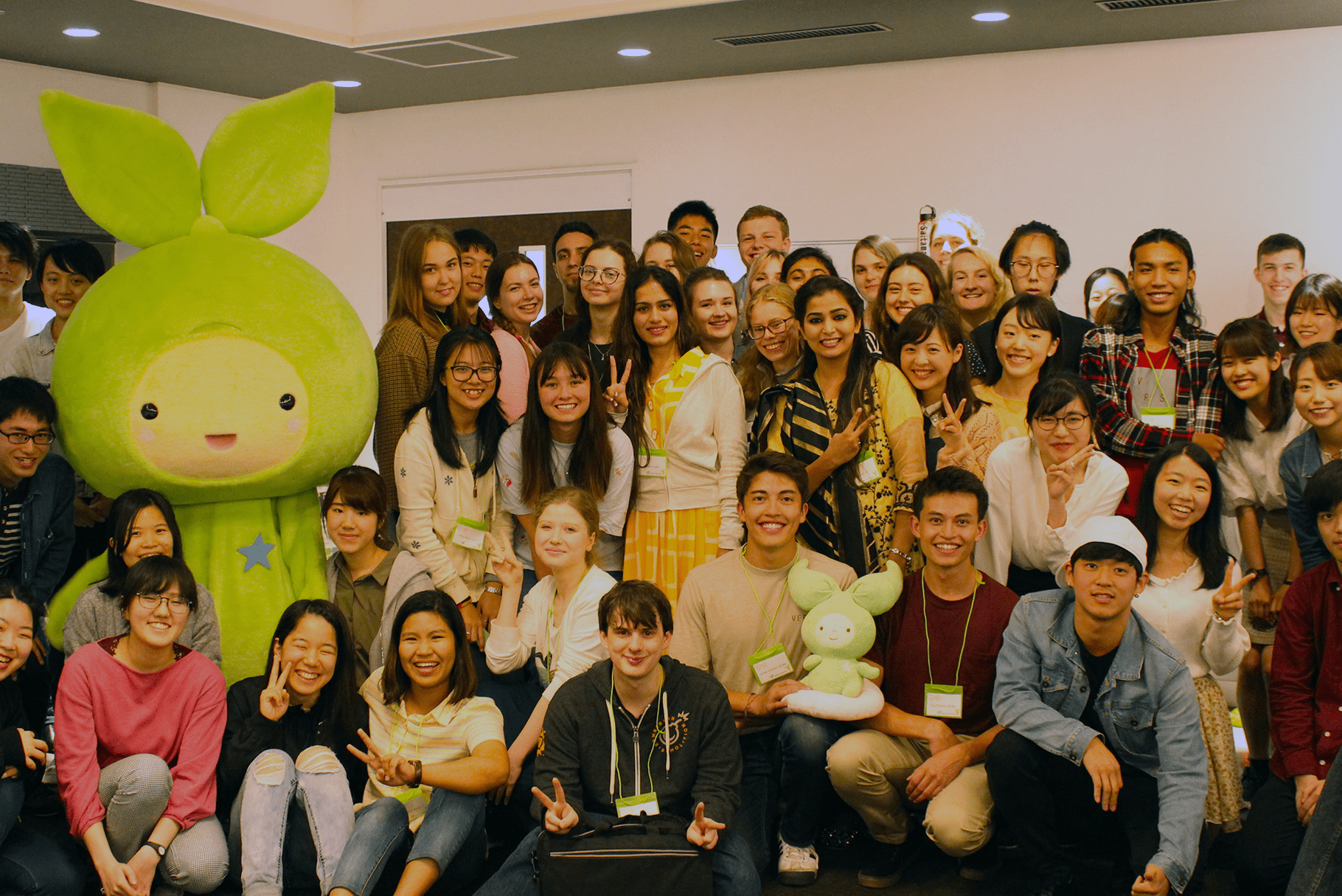 A mixture of international students posing with Saitama's mascot