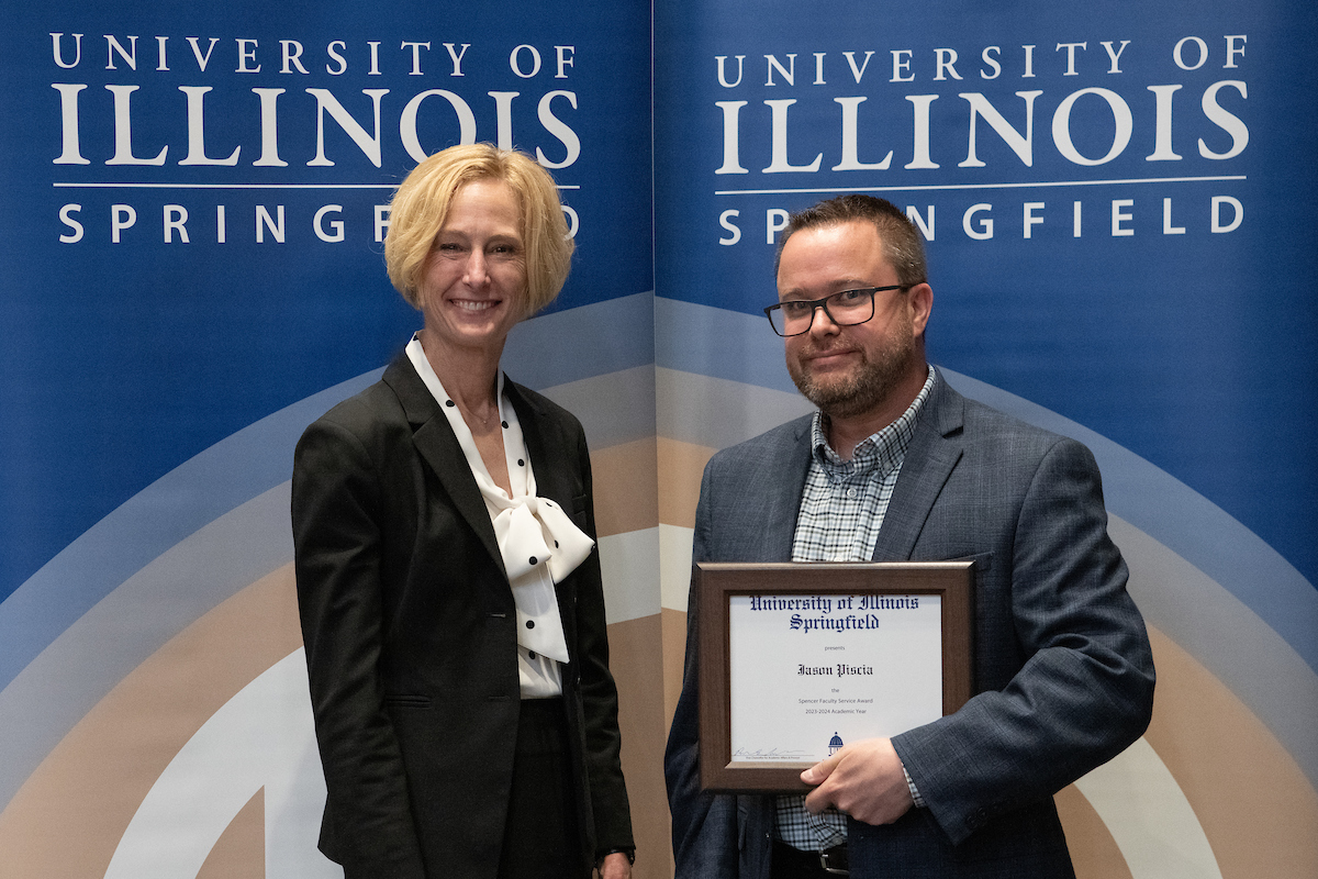 Chancellor Gooch posing with Jason Piscia who is holding an award.