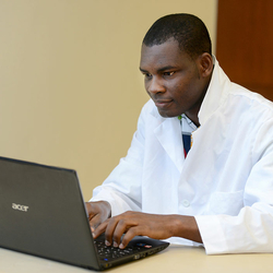 student in lab coat at computer