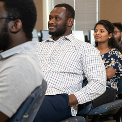People seated in a classroom, attentively facing forward.