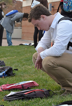 Student looking at backpack on the ground