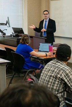 Professor Serkan Karadas teaches a class with three students visible in the photo.