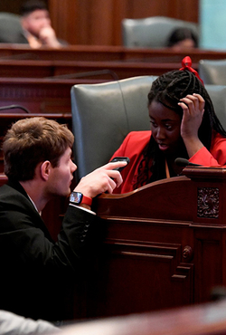 Two students speak to each other on the Illinois House of Representatives floor.