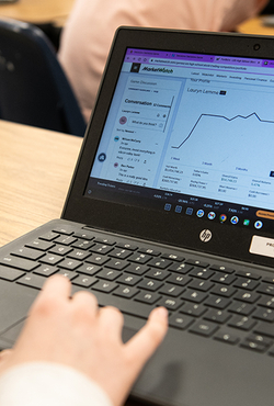 A hand on a laptop computer with the screen showing the MarketWatch platform.