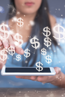 A person using a tablet with dollar signs appearing