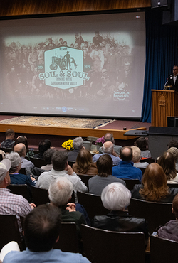Audience watching the premiere of Soil & Soul at UIS in November 2024, with a speaker at the podium.