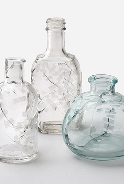  Three uniquely designed glass bottles displayed together, showcasing their distinct shapes and patterns.