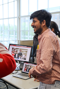 Student smiles while presenting a project on a laptop during a campus event.