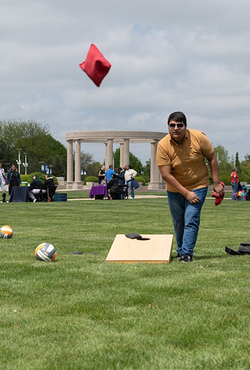 Students play lawn games during a campus health fair on the UIS quad, with booths and the colonnade visible in the background.