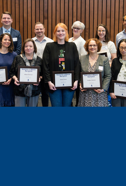 Ten faculty members pose for a photo holding their awards. 