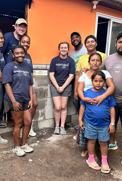A group of UIS students and local residents stand in front of a newly built home during a service trip in Guatemala.