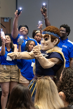 Orientation leaders dance around UIS mascot Orion at a First-Year Student Orientation event.