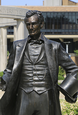 Statue of Abraham Lincoln with the UIS colonnade in the background.