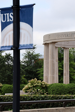 University Colonnade and a UIS banner, overcast sky.