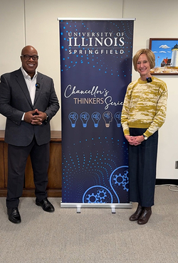 Two people standing beside a University of Illinois banner indoors.