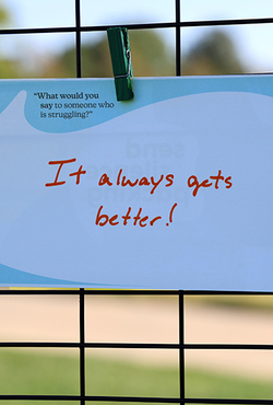 Sign clipped to a fence reads, "It always gets better!"