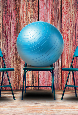 Blue exercise ball on chair between two folding chairs, wood-textured background.