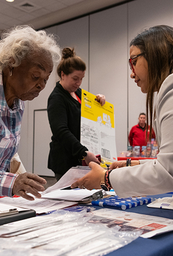 People interacting at a table with documents and supplies.