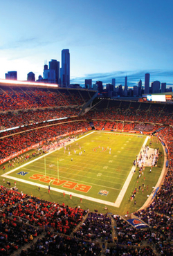 Football stadium at dusk with city skyline in background.