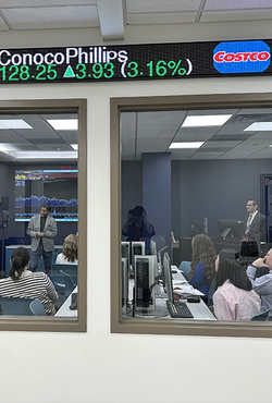 People in a conference room watching a financial presentation.