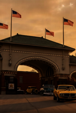 Historic gateway at sunset, vintage cars parked, flags waving.