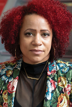 A woman with curly red hair, wearing a floral jacket and hoop earrings.