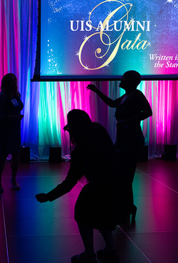 Silhouetted dancers at a colorful gala event.