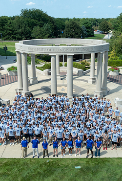 Large group of people in front of a circular monument with columns.