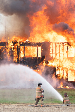 Firefighters extinguishing a large building fire with hoses.