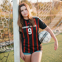 Rowan Severson holding a soccer ball and leaning on a goal