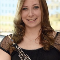 Suzanne Segredo smiling and holding a musical instrument indoors.