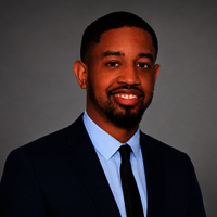 Smiling man in a suit with a gray background.
