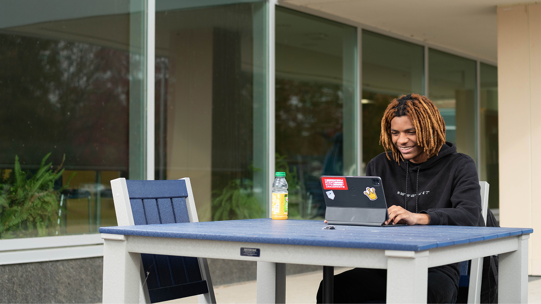 Student studying outdoors on a laptop at a campus table