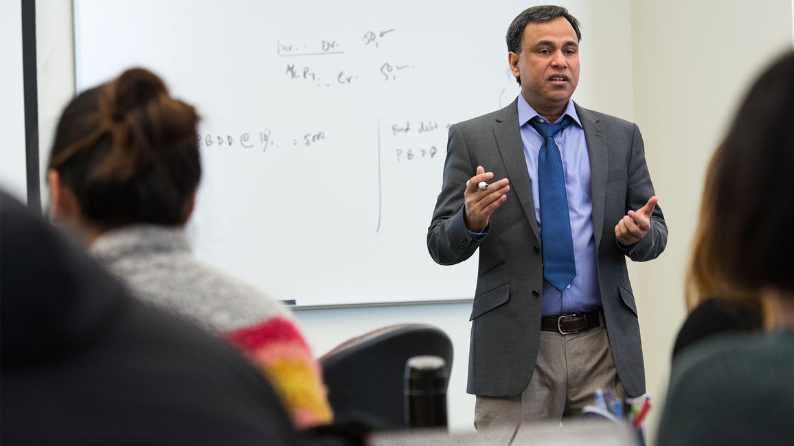 UIS professor Mohammed Mohi Uddin teaching a class using hand gestures in a classroom. 