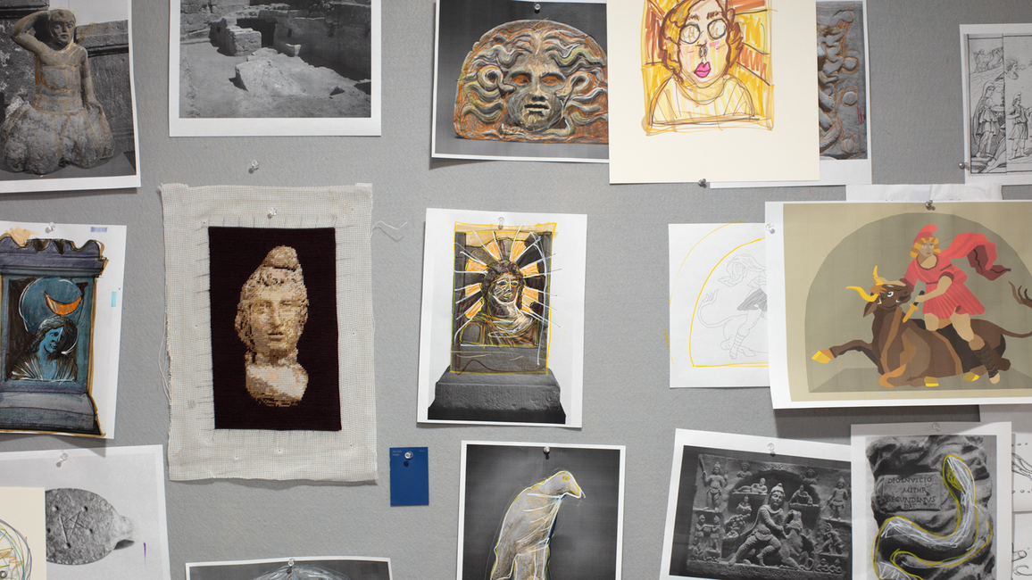 Pieces of paper tacked to a board featuring faces and shapes.