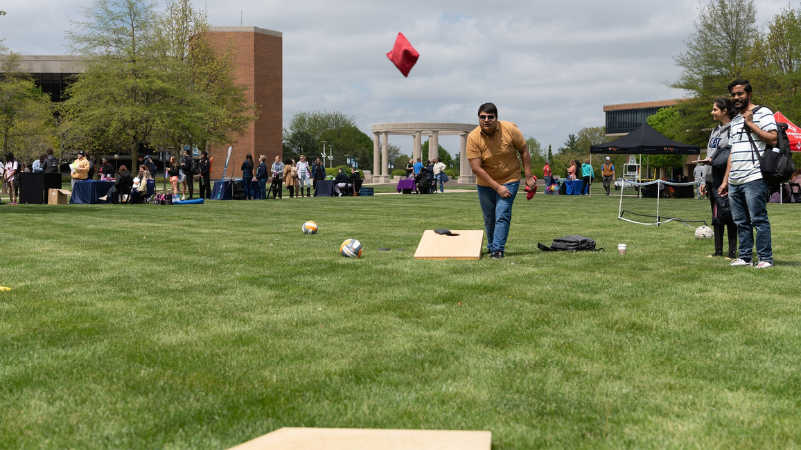 Students play lawn games during a campus health fair on the UIS quad, with booths and the colonnade visible in the background.