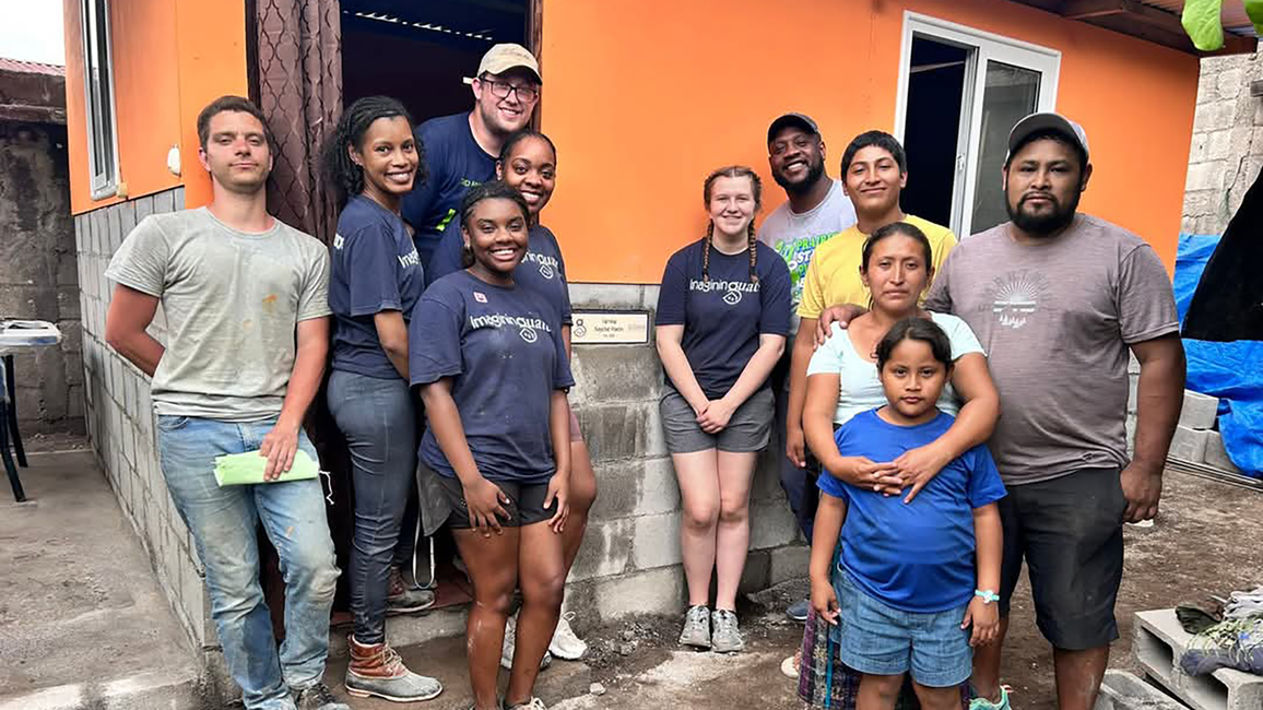 A group of UIS students and local residents stand in front of a newly built home during a service trip in Guatemala.