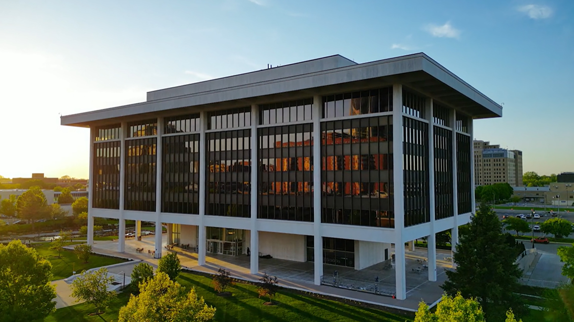 Horace Mann building in downtown Springfield at sunset, with trees and sidewalks in the foreground.