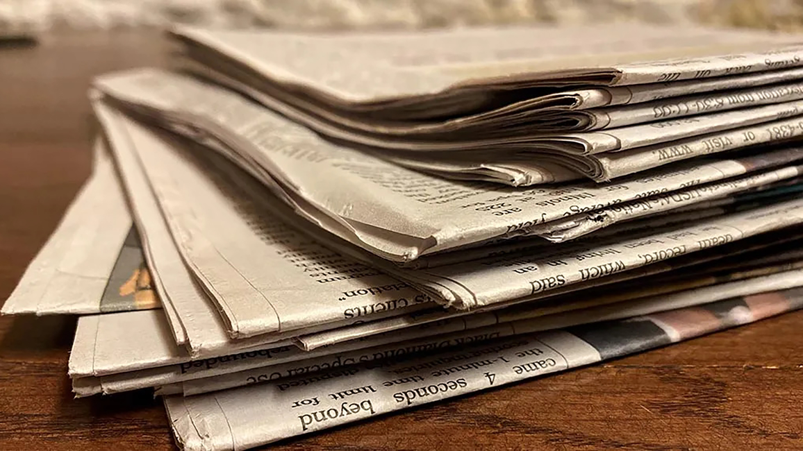 A stack of newspapers on a desk.