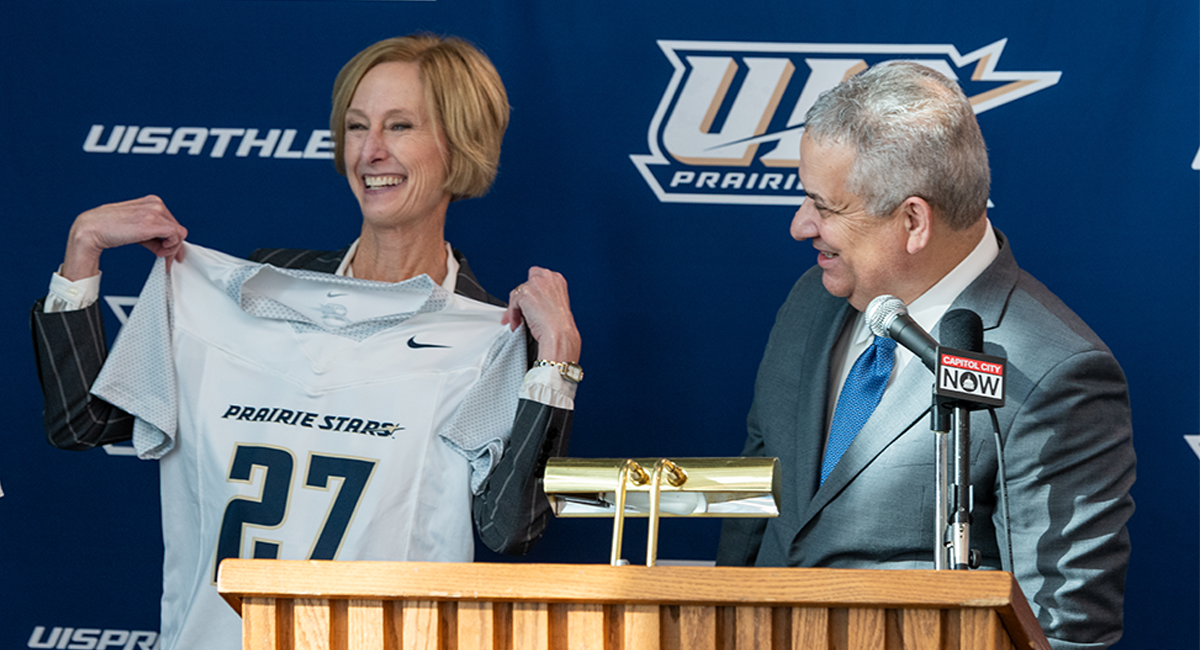 Chancellor Janet Gooch holds up a UIS women's flag football jersey with Athletic Director Mike Herman.