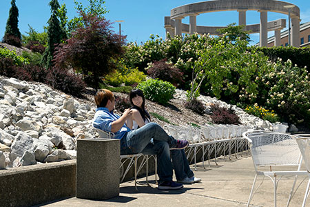 Two people relaxing on a sunny outdoor path with greenery.