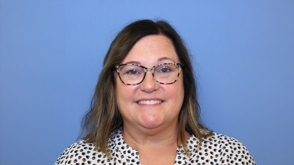 Smiling woman with glasses against a blue background.