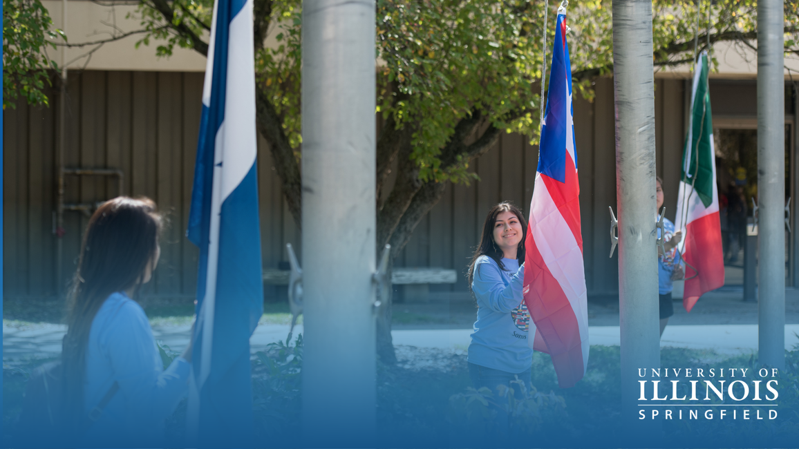 People hoisting flags outdoors on a sunny day.