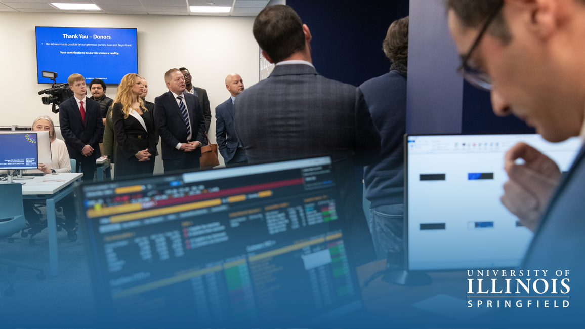 People in business attire attending a presentation, with financial data on screens.