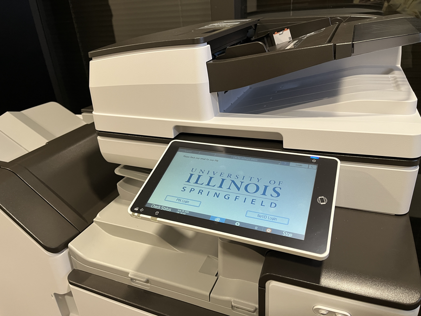 Printer with a touchscreen display featuring a university logo.
