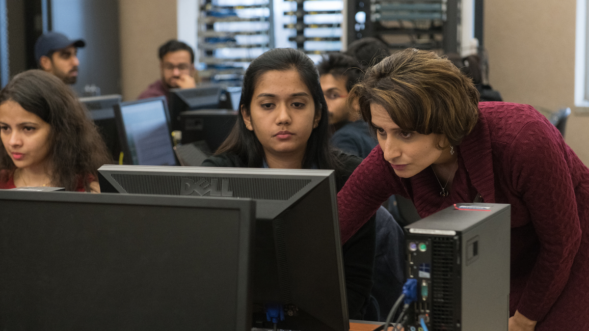 People focused on computer screens in a dimly lit room.