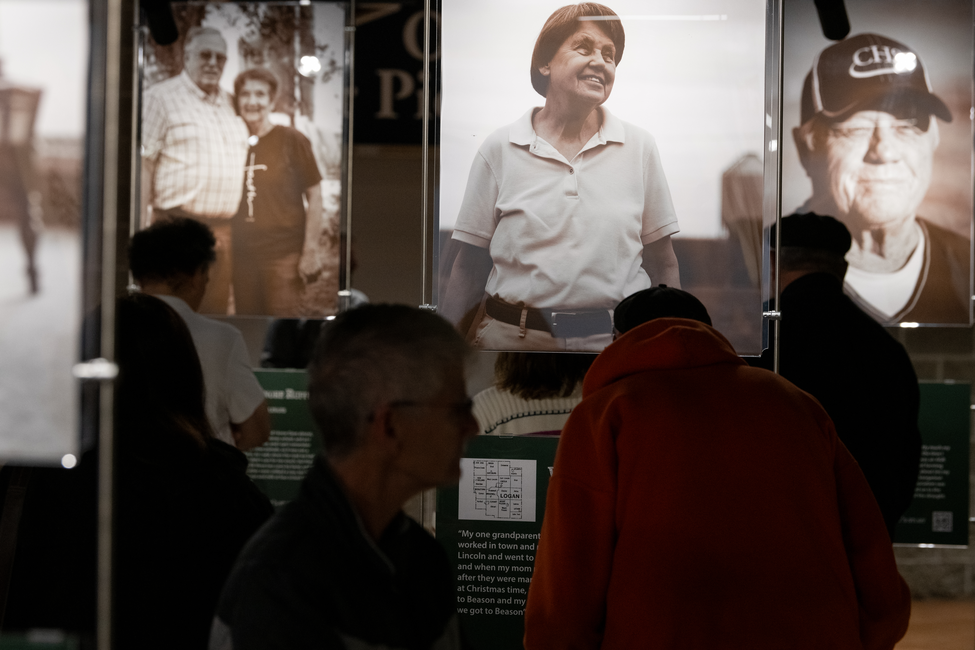 Visitors view large portrait photographs and stories in a museum-style community exhibit titled Soil & Soul..