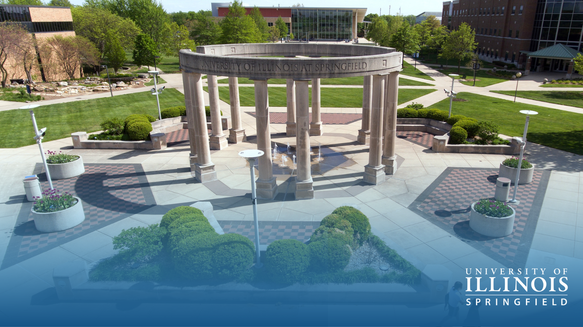 Circular stone gazebo in a sunny park, University of Illinois Springfield logo.